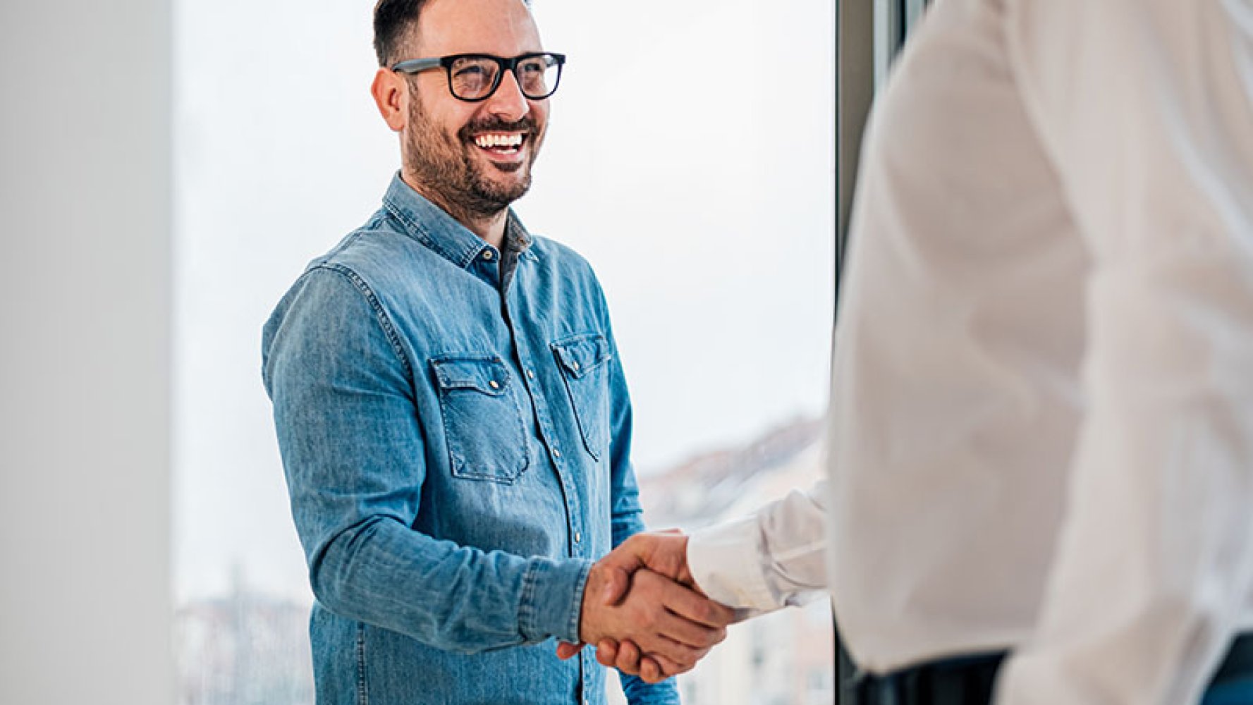 To menn tar hverandre i hånda, smilende mann.