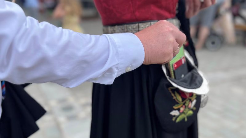 Lommetyv tar mobil ut av en bunadsveske