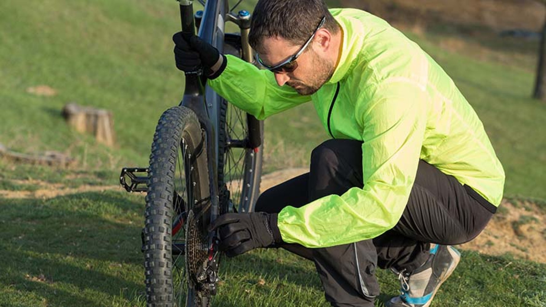 Mann kneler ved ødelagt sykkel.