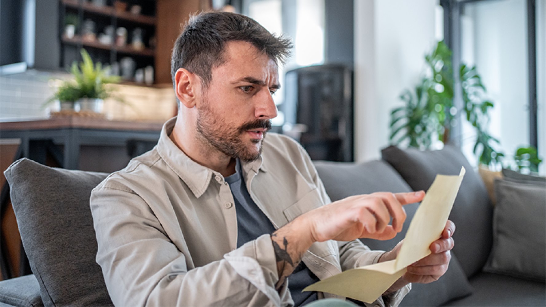 Mann leser brev og ser bekymret ut.