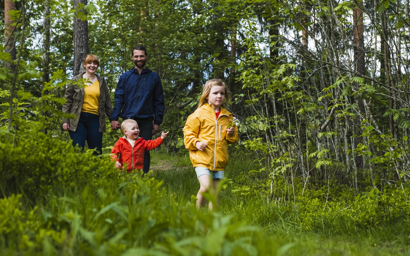 Familie ute på skogstur. Mamma og pappa bak, to barn foran. 