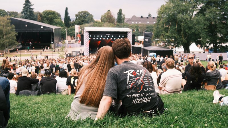 Ungt par ser ned på scenen på en musikkfestival i Oslo, sett bakfra
