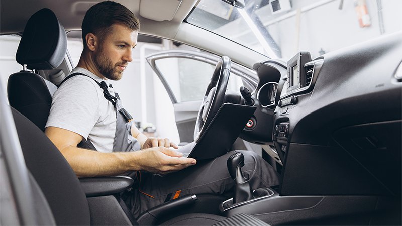 Bilmekaniker kjører diagnostikk programvare på datamaskinen.