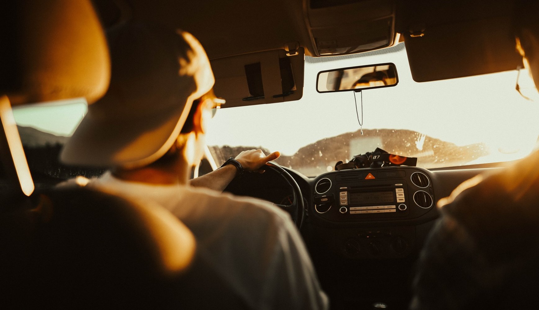 Ung sjåfør i førersetet på bil. sett fra baksetet.