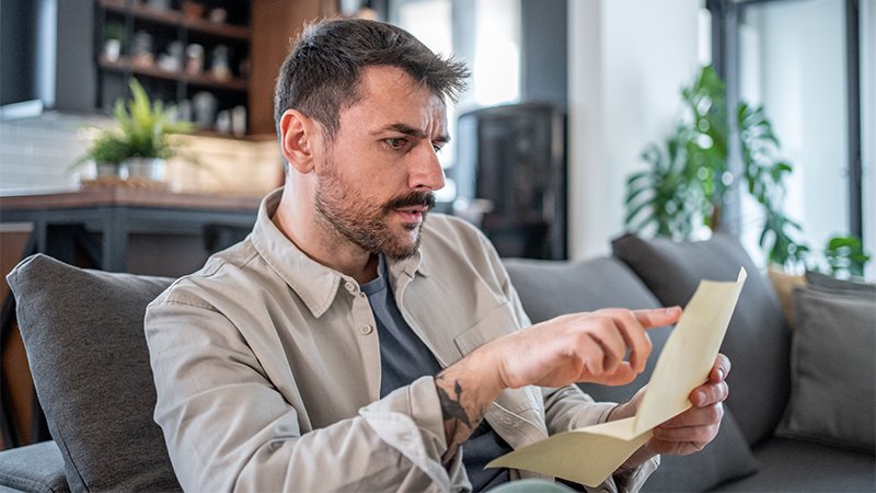 Mann leser brev og ser bekymret ut.