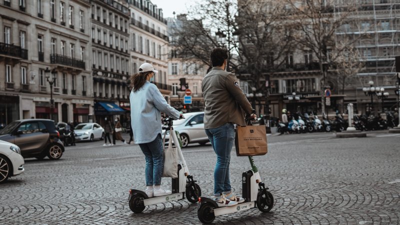 En jente og gutt på hver sin elsparkesykkel i Paris.