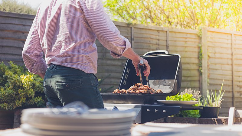 Mann som griller middag i hagen