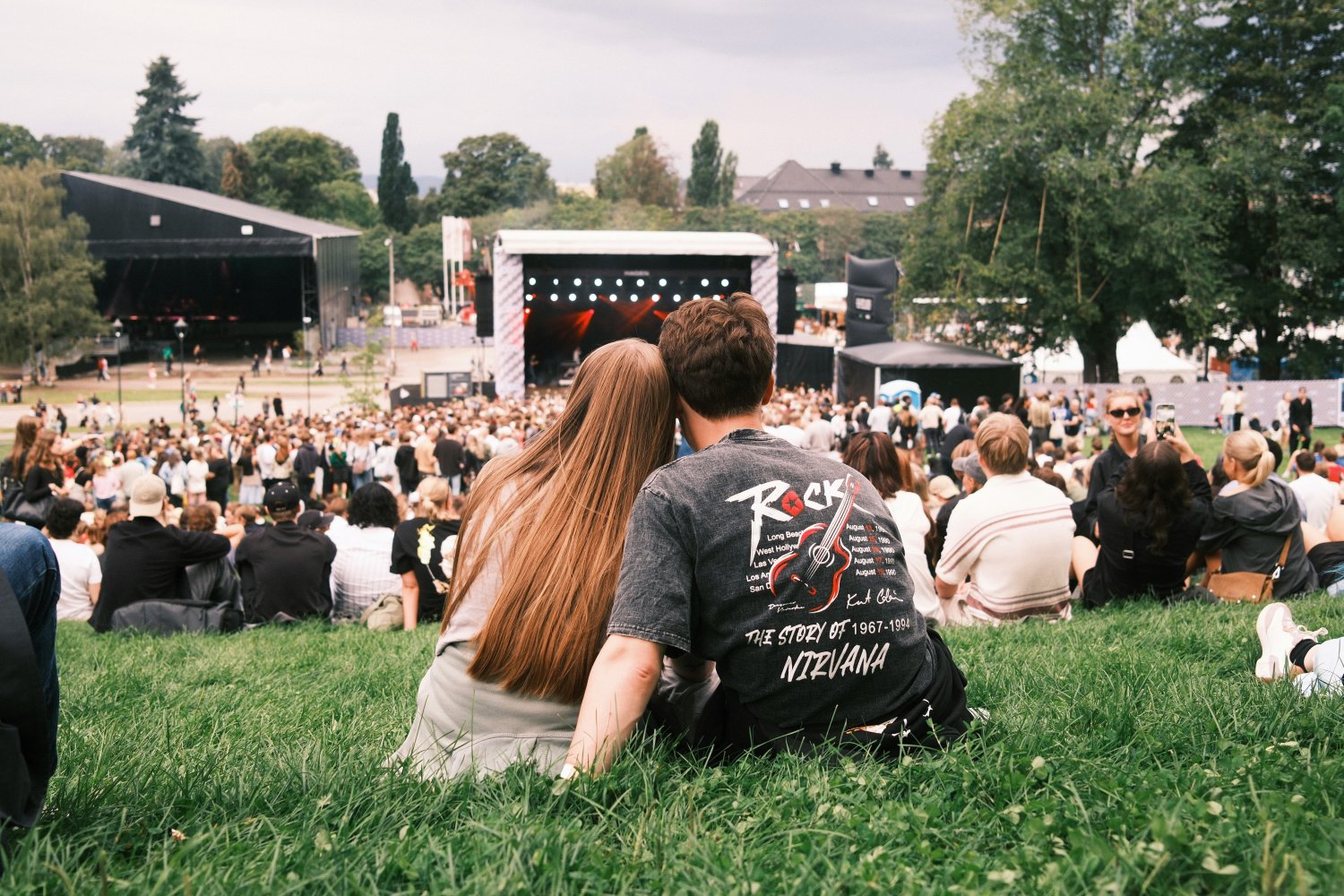 Ungt par ser ned på scenen på en musikkfestival i Oslo, sett bakfra